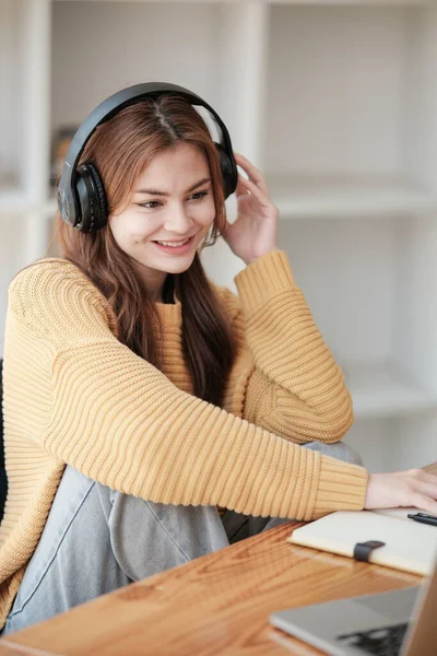 Güzel beyaz bir kız öğrenci üniversitede uzaktan öğrenim görüyor. Evde dizüstü bilgisayar ve not defteriyle bir masada oturuyor ve bir video konferans dersi izliyor. Yüksek kalite