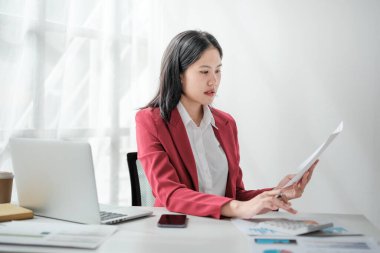 Ofis bilgisayarında çalışan kırmızı takım elbiseli güzel Asyalı kadının portresi. Küçük işletme... yüksek kaliteli fotoğraf.