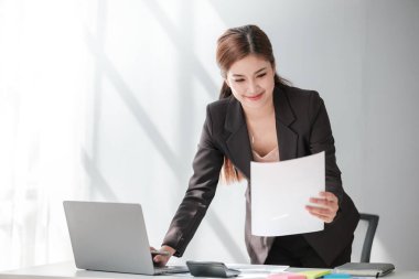 Asyalı İş kadını, bir ofis masası, vergi, rapor, muhasebe, istatistik ve analitik araştırma konseptinde matematik finansmanı için hesap makinesi ve dizüstü bilgisayar kullanıyor. Yüksek kalite fotoğraf