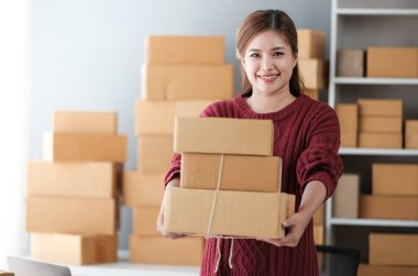 Girişim KOBİ küçük işletme girişimcisi önlük giyen Asyalı kadın dizüstü bilgisayar ve kutu kullanarak çevrimiçi müşterilere, çevrimiçi sme iş fikirlerine satış hazırlamak için siparişleri alır ve gözden geçirir