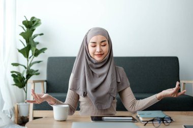 Müslüman kadın çalışan ofiste çalışırken meditasyon yapıyor. Yüksek kalite fotoğraf