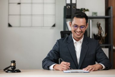 Masa başında çalışan Asyalı avukat bir belge, hukuk ve adalet kavramı yazıyor. Yüksek kalite fotoğraf