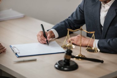 Masa başında çalışan Asyalı avukat bir belge, hukuk ve adalet kavramı yazıyor. Yüksek kalite fotoğraf