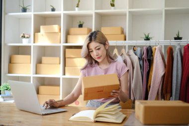 Çevrimiçi alışveriş kavramı, kadın girişimci siparişi onaylar ve paket kutularına adres yazar. Yüksek kalite fotoğraf