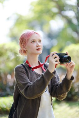 Çiçek bahçesinde fotoğraf çeken güzel genç bir sanatçı. Genç tatlı kız bahçede kamerayı taşıyor. Yüksek kalite fotoğraf