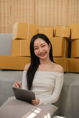 Başarılı bir iş kadını, internet üzerinden paket satarken ve ev kadınına paket teslim ederken, dizüstü bilgisayar ve KOBİ iş konsepti siparişlerini kontrol ederken eğleniyor. Yüksek kalite fotoğraf