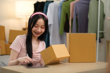 Evde çalışan küçük bir işletme sahibi, eve teslimat siparişi için paket kutusuna adres yazan bir kadın, online alışveriş işi, ekommence konsepti. Yüksek kalite fotoğraf