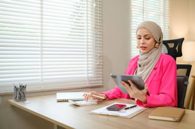Pembe ceketli bir kadın önünde tabletle bir masada oturuyor. O bir klavye üzerinde yazıyor ve tablete bakıyor. Verimlilik ve odaklanma kavramı