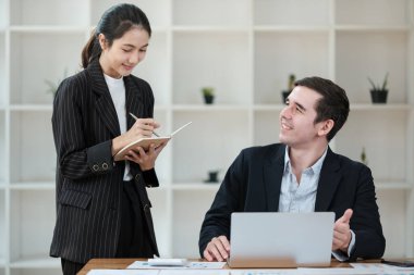 Bir kadın not defterine yazı yazarken bir erkek bakıyor. Sahne masada dizüstü bilgisayarı olan bir ofiste geçiyor. Kadın yazarken gülümsüyor, erkek de mutlu.