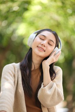 Kulaklık takan bir kadın gülümsüyor ve müziğinden hoşlanıyor gibi görünüyor. Rahatlama ve memnuniyet kavramı