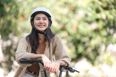 Bir kadın kask takıp bisiklete binerken gülümsüyor. Mutluluk ve macera kavramı, kadın bisiklete binmeye hazır.
