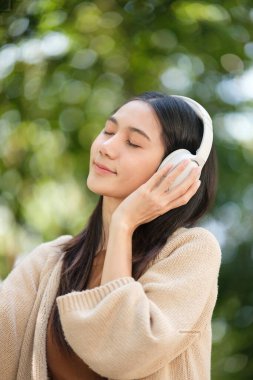 Kulaklık takan bir kadın gülümsüyor ve müziğinden hoşlanıyor gibi görünüyor. Rahatlama ve memnuniyet kavramı