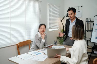 Üç kişi konferans odasında bir masada oturmuş iş meselelerini tartışıyorlar. Takım elbiseli adam grubun lideri, iki kadın ise meslektaşı.