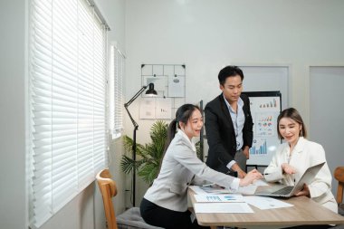 Üç kişi önlerinde bir laptop ve kağıtlarla bir masada oturuyorlar. Önemli bir şeyi tartışıyorlar, muhtemelen işle ya da bir projeyle ilgili. Atmosfer ciddi ve odaklanmış görünüyor.