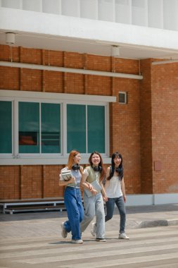 Sokakta yürüyen üç genç kadın, biri elinde kitap tutuyordu. Sahne aydınlık ve neşeli, kızlar birlikte eğleniyor gibi görünüyor.