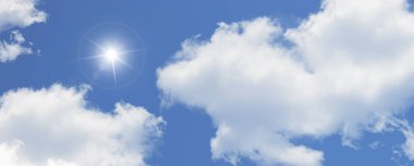 Güneş gökyüzünde parlıyor büyük beyaz bulutların arasında