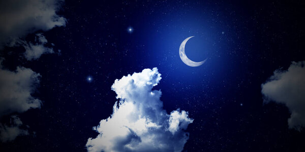 Crescent moon illuminating clouds in midnight sky. Night sky and shining stars.