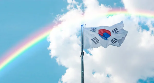 Rainbow and flag of South Korea. South Korea flag waving in the blue sky.