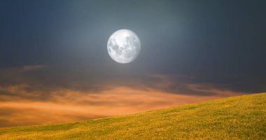 Günbatımında dolunay. Gece gökyüzü ve sararmış otlarla tepe manzarası..