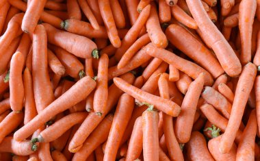 Havuç desenli fotoğraf. Yerel pazarda tezgahın üzerine taze havuç yığını. Tam kare organik havuç..