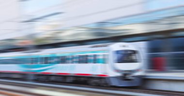 Tren istasyonunda hızlı tren hareket ediyor. Hareket bulanıklığı etkisi. Banliyö treni. Şehirlerarası yolcu treni. Ulaşım, seyahat kavramı.
