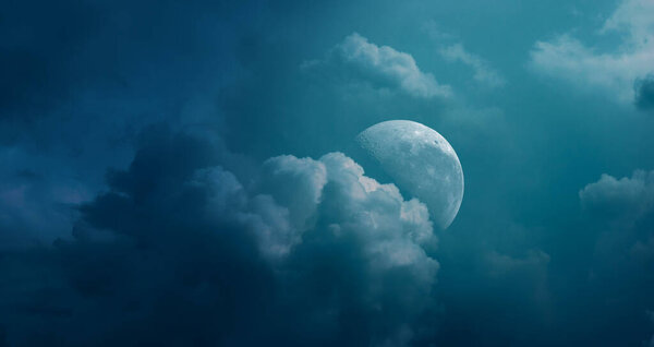 Moon behind clouds in dark night sky.