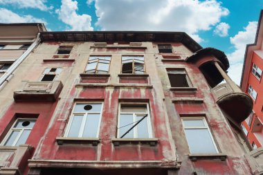 Şehir merkezinde yıpranmış dış ve kırmızı duvarları olan terk edilmiş tarihi bir bina..