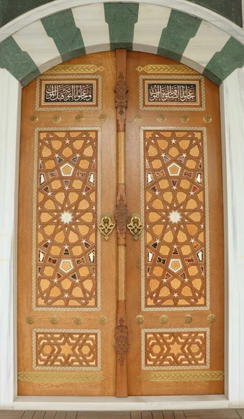 Mosque door. Closed wooden door decorated with traditional Islamic motifs. Front view of decorative historic ornate door.