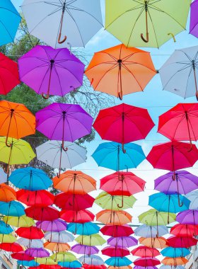 Sokakta asılı renkli şemsiyelerin dipteki görüntüsü.