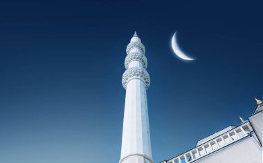 Cami minaresinin dipteki görüntüsü. İslami arkaplan. Gökyüzünde parlayan hilal. İslam bayramları ve tebrik kartları için arkaplan resmi.