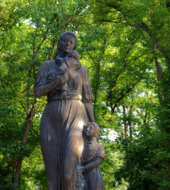 Halk parkında çocuklarını kucaklayan bir anne ve çocuğun heykeli. Anneler Günü konsepti fotoğrafı. Annenin Papa Cenapları..