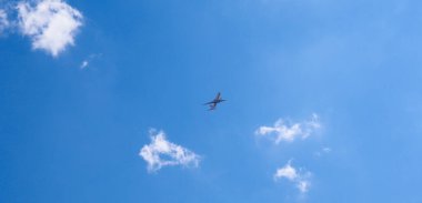 Yolcu uçağı yazın mavi gökyüzünde küçük bulutların arasında uçuyor. Turizm ve havayolu yolcu taşımacılığı