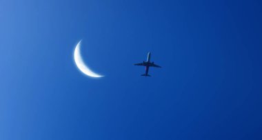 Koyu mavi gökyüzünde parlak hilal ve uçan yolcu uçağı. Turizm, kargo, ulaşım ve seyahat kavramı arka plan resmi