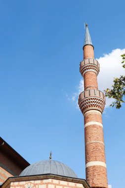 Tuğladan yapılmış tarihi bir caminin kubbesi ve minaresi.