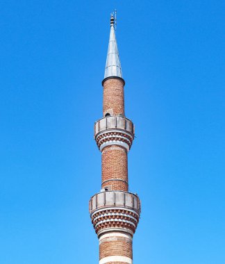 Mavi gökyüzü arka planında tarihi cami tuğlalarından yapılmış bir minare. İslami arka plan.