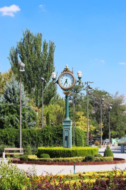 Şehir merkezindeki parkın ortasında çiçeklerdeki antika analog saat
