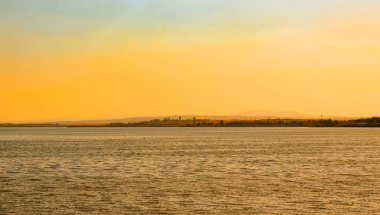 Turuncu gökyüzü ve sakin deniz yüzeyi ile gün batımı manzarası. Sahilden denize doğru bak.. 