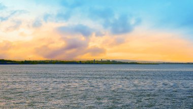 Gün batımı manzarası. Turuncu renkli gökyüzü ve sakin deniz yüzeyi. Sahilden denize doğru bak.. 