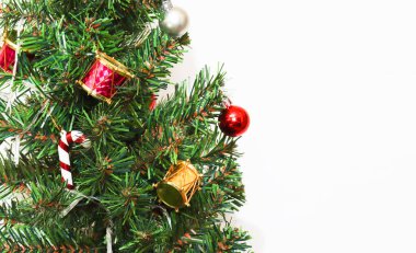 Yeşil çam ağacı dalları ve beyaz arka planda Noel süslemeleri. Yılbaşı ve Noel kutlaması için arkaplan resmi.
