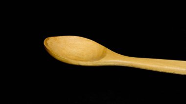 Yeni, boş, el yapımı ve temiz tahta kaşık siyah arka planda izole edilmiş..