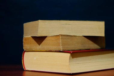 Kara duvara yaslanmış bir yığın kitap. Tahta masadaki antika kitaplar. Eski kitap fotoğrafı..