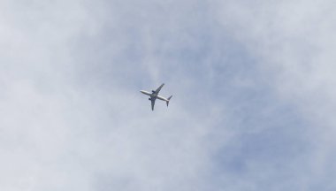 Uçan bir yolcu uçağı ve yazın bulutlarla kaplı mavi gökyüzü. Ulaşım, ulaşım ve havacılık kavramı arkaplan resmi.