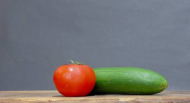 Taze biçilmiş doğal, organik domatesler ve ahşap masadaki salatalıklar..