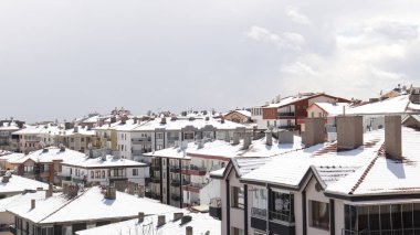 Kış sezonu sahnesi. Şehirdeki binaların çatıları karla kaplı.