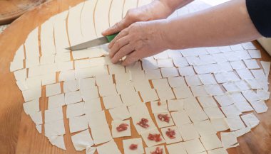 Manti hamuru hazırlayan kadının eli. Ahşap bir masada pişmemiş ev yapımı et manti. Geleneksel Türk yemeği.