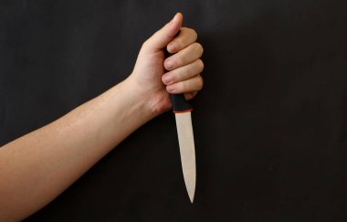 Siyah arka planda keskin bir bıçak tutan el. Suç mahalli, cinayet, saldırgan ve suç artışı kavramı arkaplan resmi.