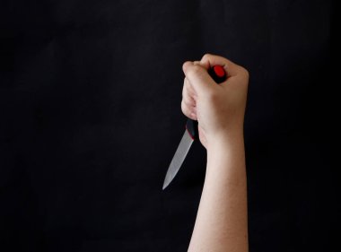 Siyah arka planda keskin bir bıçak tutan bir adam..