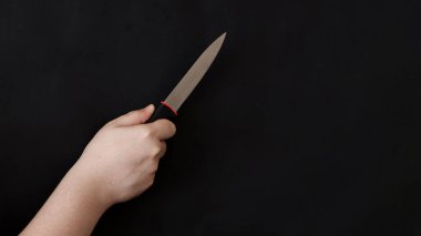 Siyah arka planda sivri ve keskin bir bıçak tutan bir adamın eli. Suç, cinayet, öldürücü kavram arkaplan resmi.
