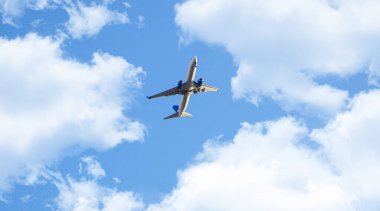 Mavi gökyüzündeki bulutların arasından yükselen uçak. Büyük yolcu uçağı az önce havaalanından havalandı. Ulaşım, tatil ve seyahat konsepti fotoğrafı.