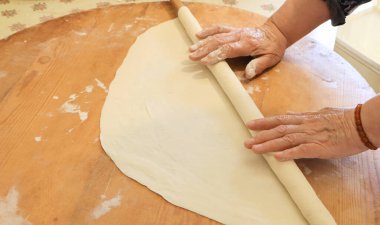 Bir kadının hamuru merdaneyle yuvarlanıyor. Tahtaya hamur işi ve hamur işi..